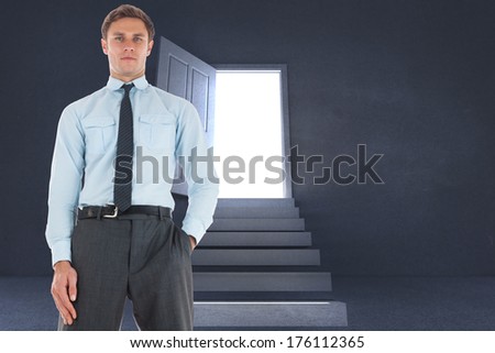 Serious businessman standing with hand in pocket against steps leading to open door showing light