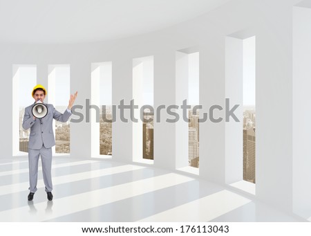 Architect with hard hat shouting with a megaphone against bright white room with windows
