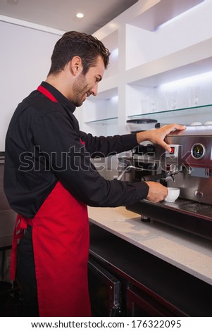Smiling attractive barista making cup of coffee in a cafe