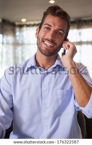 Happy businessman talking on the phone after work in a bar