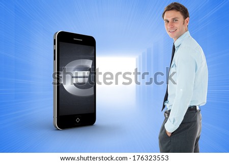 Happy businessman standing with hand in pocket against bright blue room