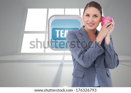 Smiling bank clerk shaking piggy bank against bright room with windows