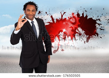 Businessman showing okay sign against splash showing cogs and wheels