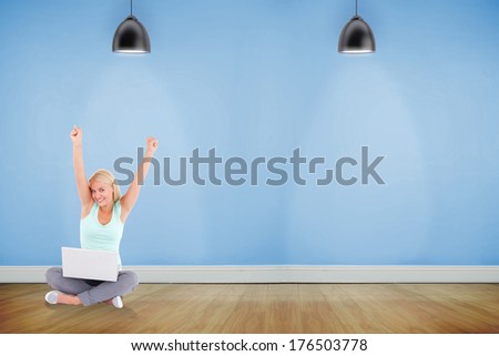 Joyful woman with a notebook against room with wooden floor lighted with spotlights