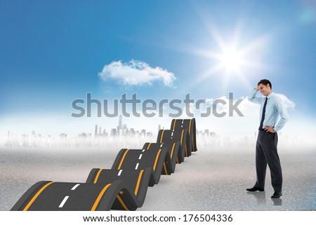 Thoughtful businessman with hand on head against bumpy road leading to city