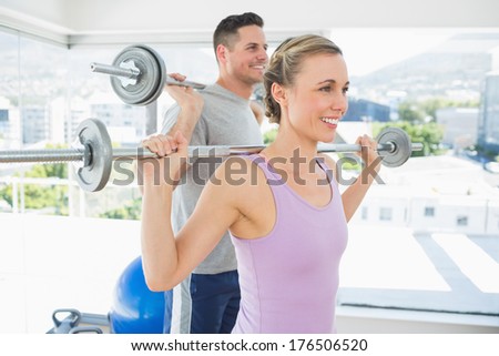 happy fit woman and man lifting barbells in the exercise room