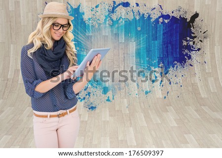 Smiling Trendy Blonde Using Tablet Computer Against Splash Showing Blue Light