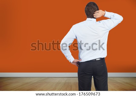 Thinking businessman scratching head against room with wooden floor
