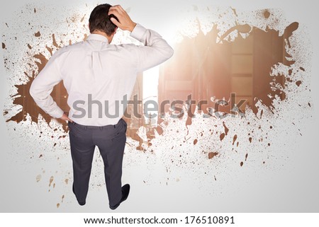Thinking businessman scratching head against splash on wall revealing cityscape