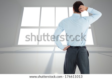 Thinking businessman with hand on head against bright room with windows
