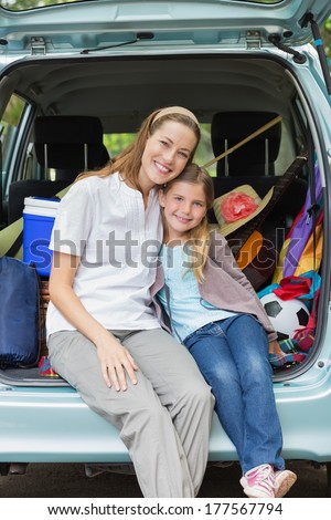 Portrait of a smiling mother and daughter sitting in car trunk while on picnic