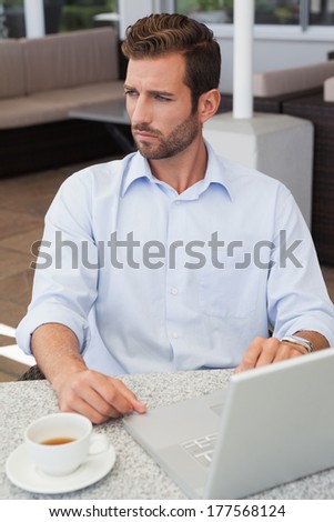 Focused businessman working with laptop at table in patio of restaurant