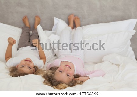 Portrait of two smiling young kids lying in bed at home