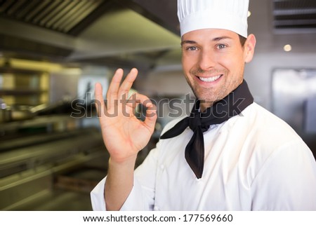 Closeup portrait of a smiling male cook gesturing okay sign in the kitchen