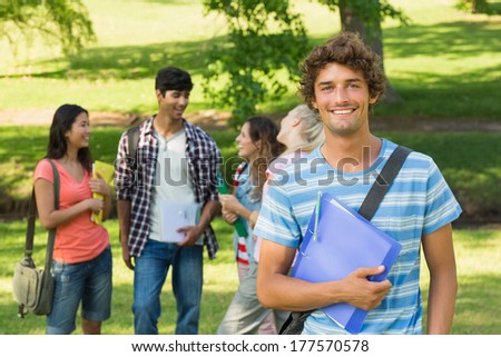 Portrait of a boy with happy college friends in background at the campus