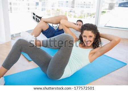 Portrait of fit couple doing sit ups in fitness studio