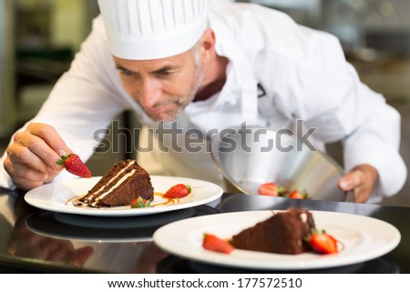 Closeup of a concentrated male pastry chef decorating dessert in the kitchen