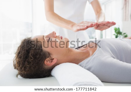 Attractive young woman having reiki treatment in health spa
