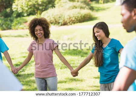 Group of young friends holding hands in a circle at the park