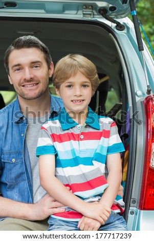 Portrait of a happy father and son sitting in car trunk while on picnic