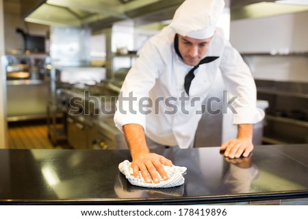 Male cook wiping the counter top in the kitchen