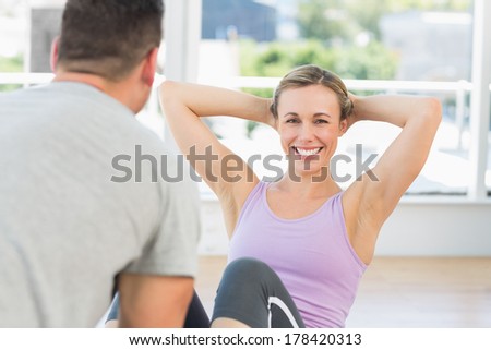 Male trainer helping woman doing sit ups in fitness club