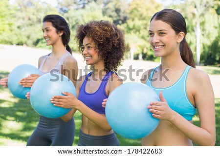 Smiling sporty women with medicine balls exercising in park