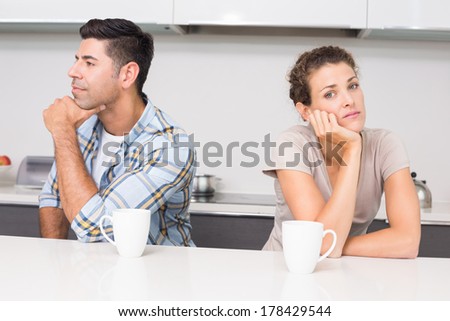 Troubled couple having coffee not talking at home in kitchen
