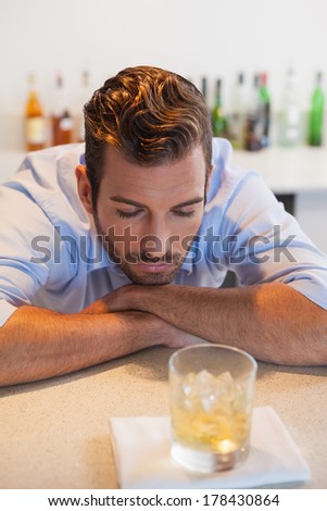 Drunk businessman looking at his whiskey glass at the local bar