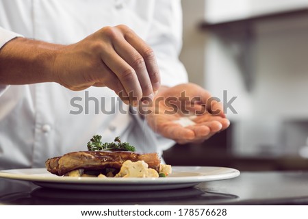 Closeup mid section of a chef putting salt in the kitchen