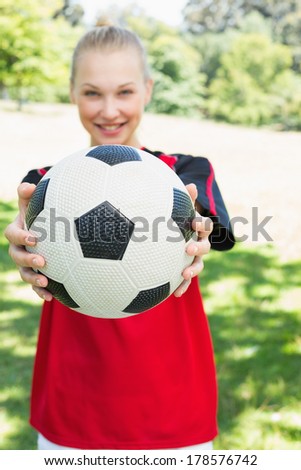 Portrait of female soccer player showing ball at park