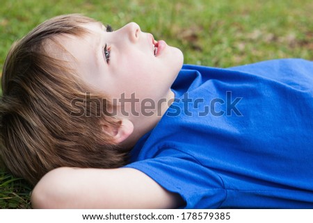 Close-up side view of a relaxed young boy lying at the park