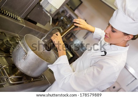 Side view of a concentrated female cook preparing food in the kitchen