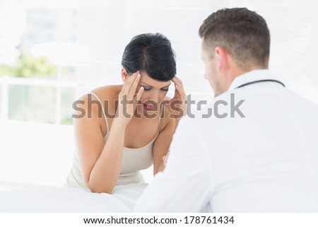 Stressed woman visiting male doctor in clinic