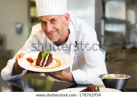 Closeup portrait of a smiling male pastry chef with dessert in the kitchen