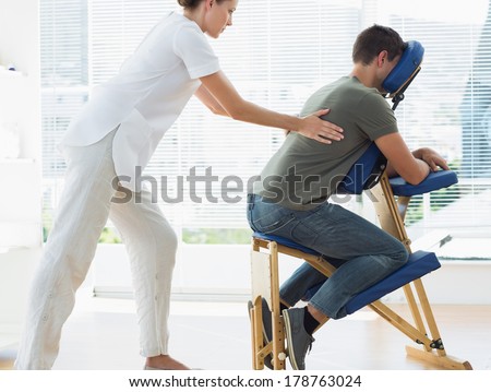 Side view of female therapist massaging man in hospital