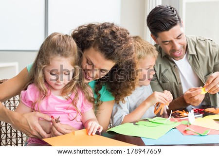 Cheerful family doing arts and crafts together at the table at home in kitchen
