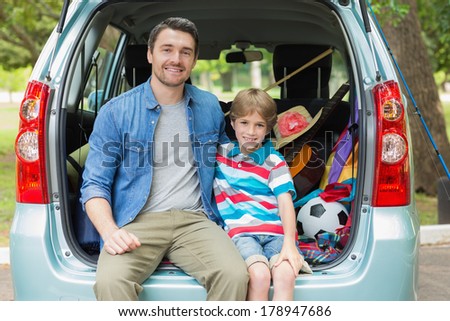 Portrait of a happy father and son sitting in car trunk while on picnic