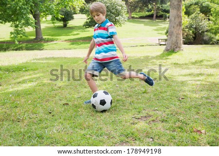 Full length of a young boy kicking ball at the park