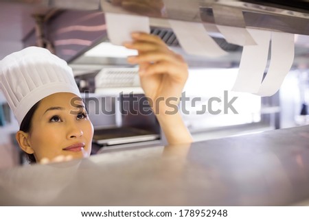 Closeup of a young female chef going through cooking checklist at kitchen counter