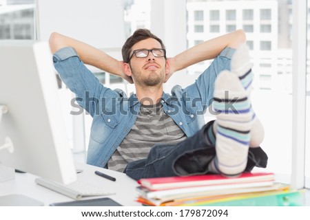 Relaxed casual young man with legs on desk in a bright office