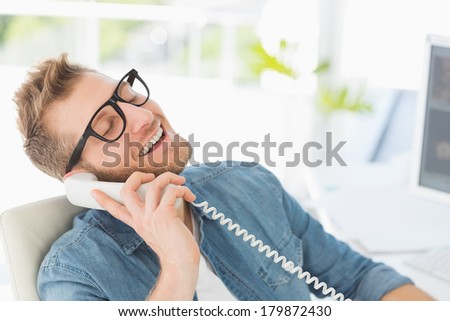 Handsome designer laughing on the telephone in creative office