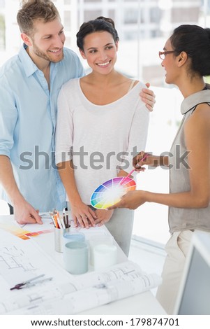 Interior designer showing colour wheel to happy clients in her studio