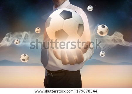Digital composite of businessman presenting floating footballs