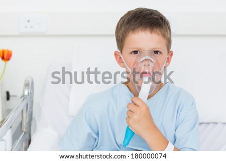 Portrait of sick little boy wearing oxygen mask in hospital bed