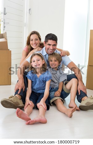 Portrait of happy children and parents sitting on floor in their new house
