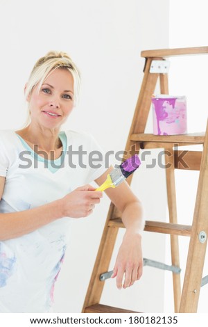 Portrait of a beautiful young woman holding paint brush in the new house