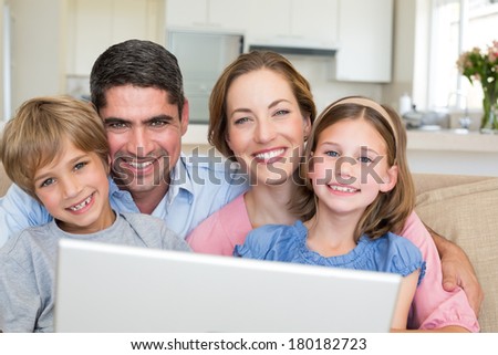 Closeup portrait of smiling family with laptop in house
