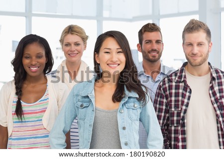 Young design team standing and smiling at camera in creative office
