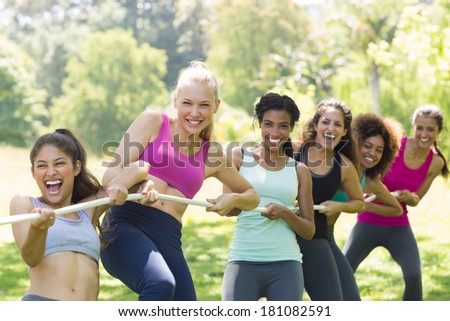 Happy women pulling a rope in tug of war at the park